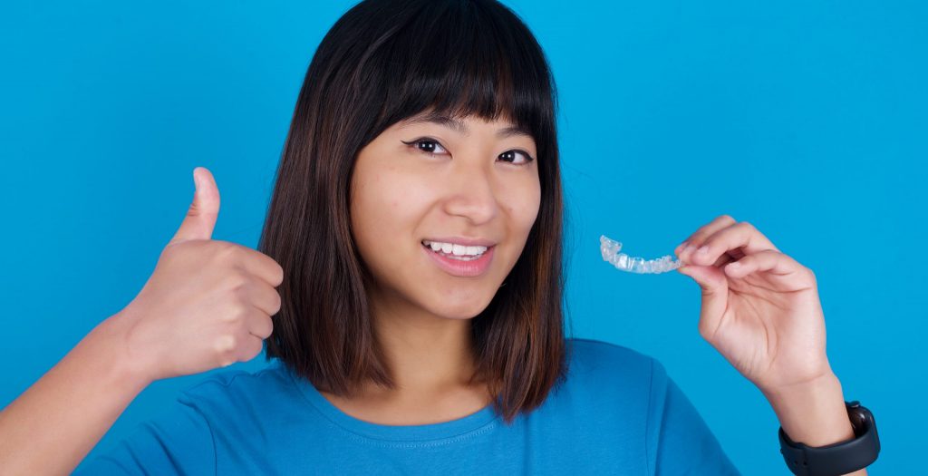happy Asian woman with clear aligner thumbs up