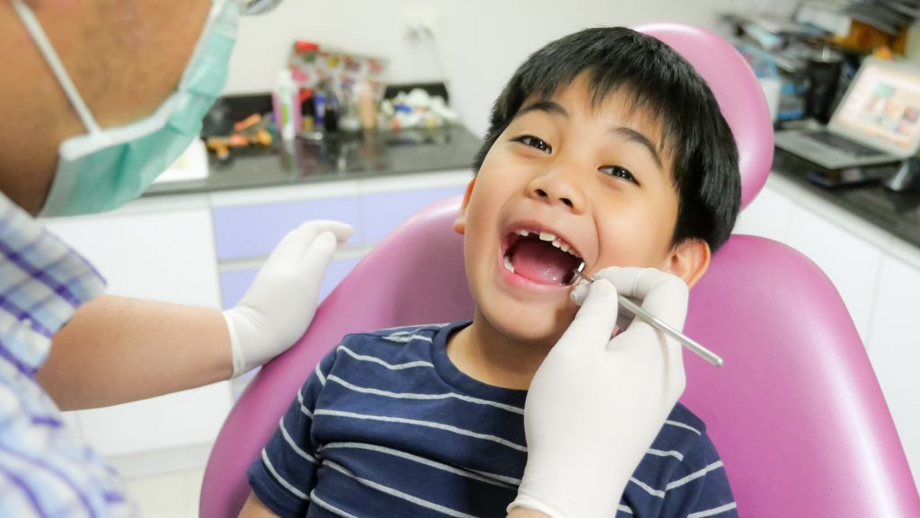 child having deciduous teeth checked by dentist
